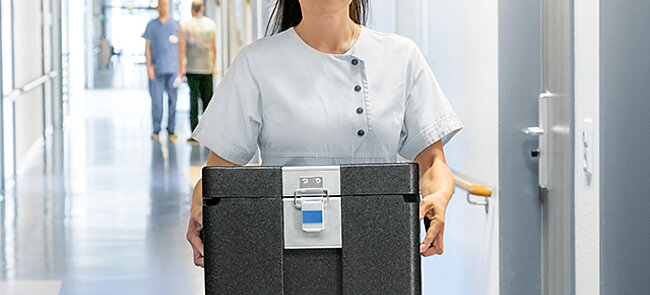 Eine Frau trägt eine schwarze Isolierbox