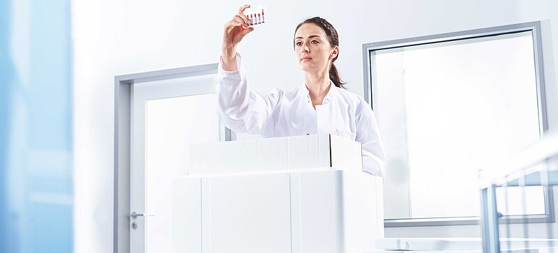 Eine Frau entnimmt aus einer Isolierbox ein Reagenzglas