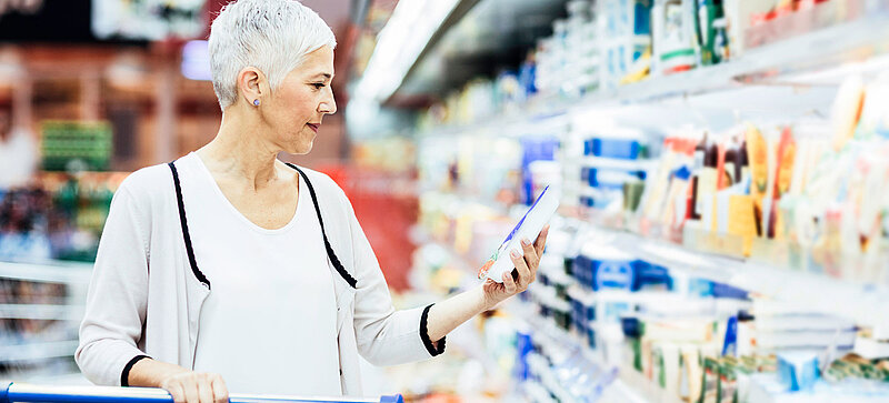 Eine Frau steht vor dem Kühlregal im Supermarkt